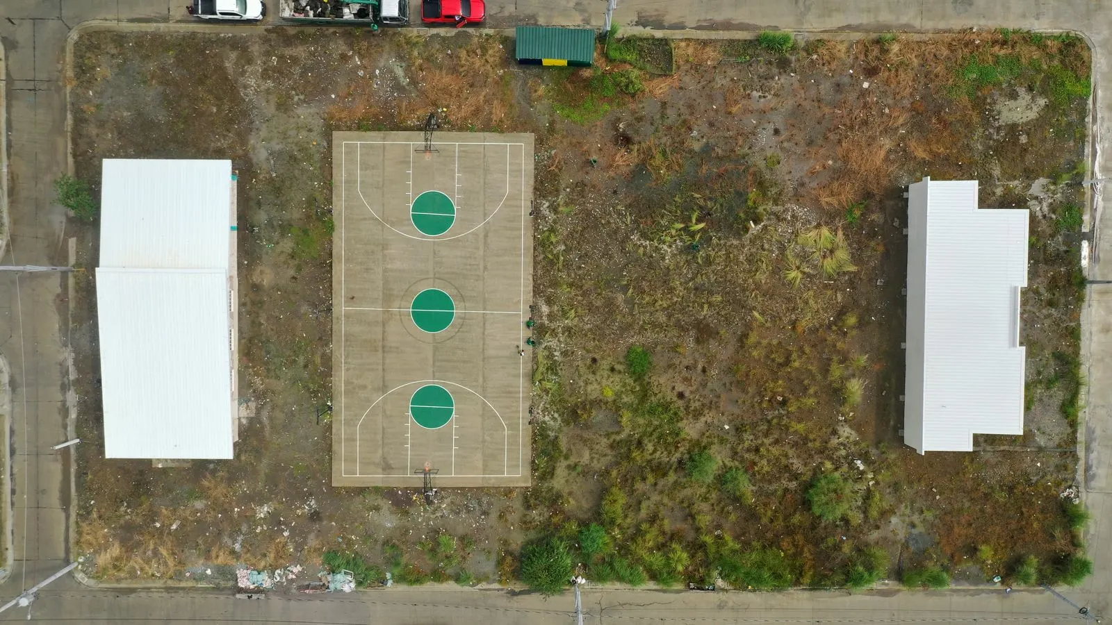 Before: bare dirt and patchy vegetation at a subdivision basketball court
