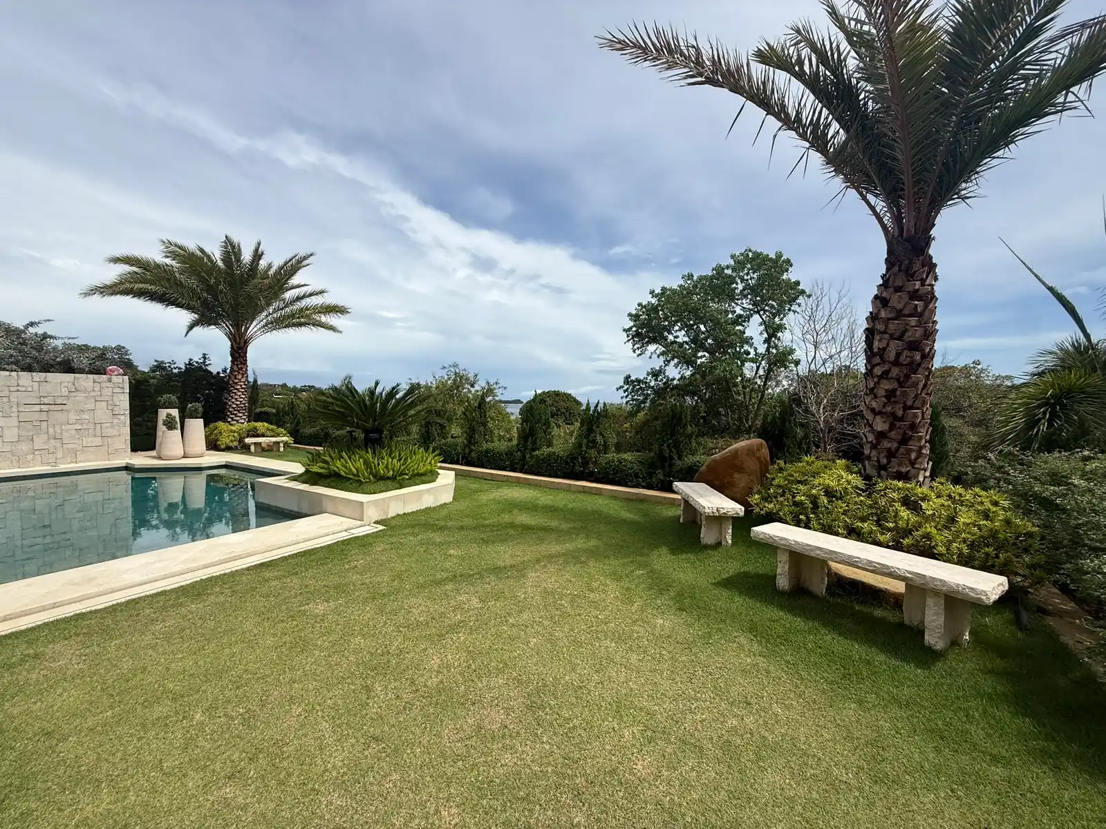 Pool terrace lined with palms and lawn at a Punta Fuego private estate