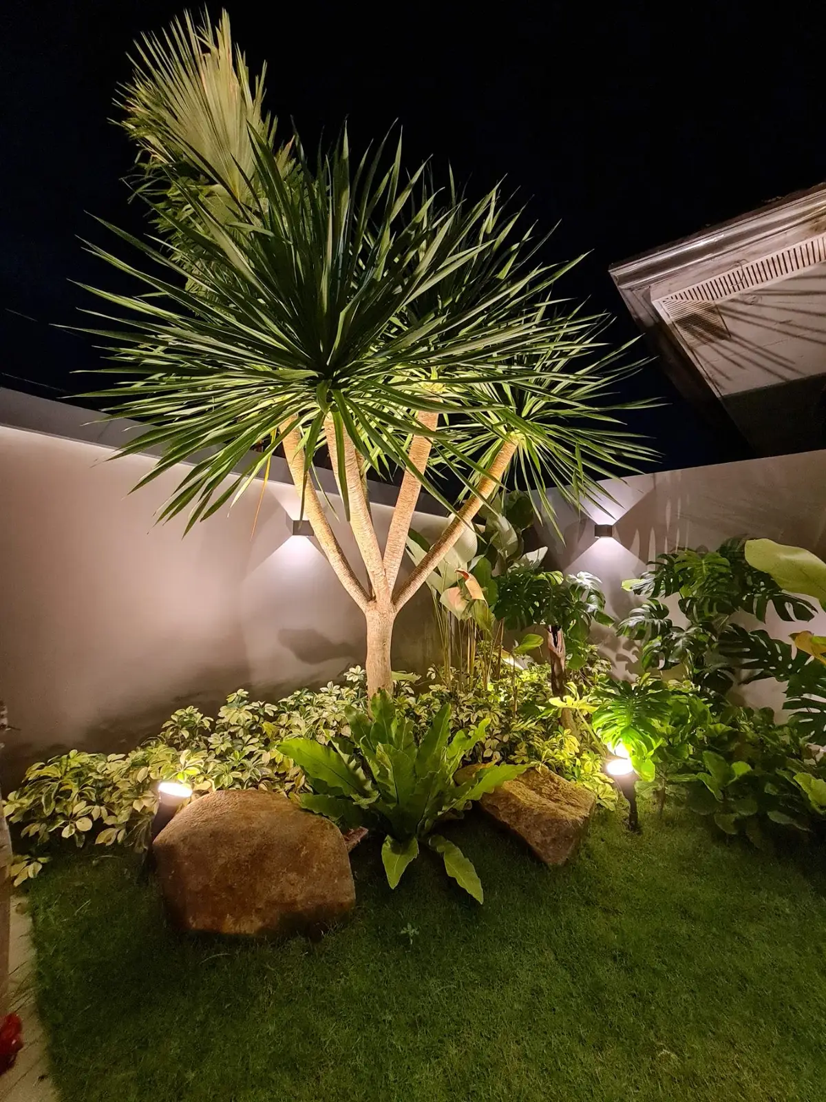 Night-lit boulder and paving feature with landscape lighting at a residential property