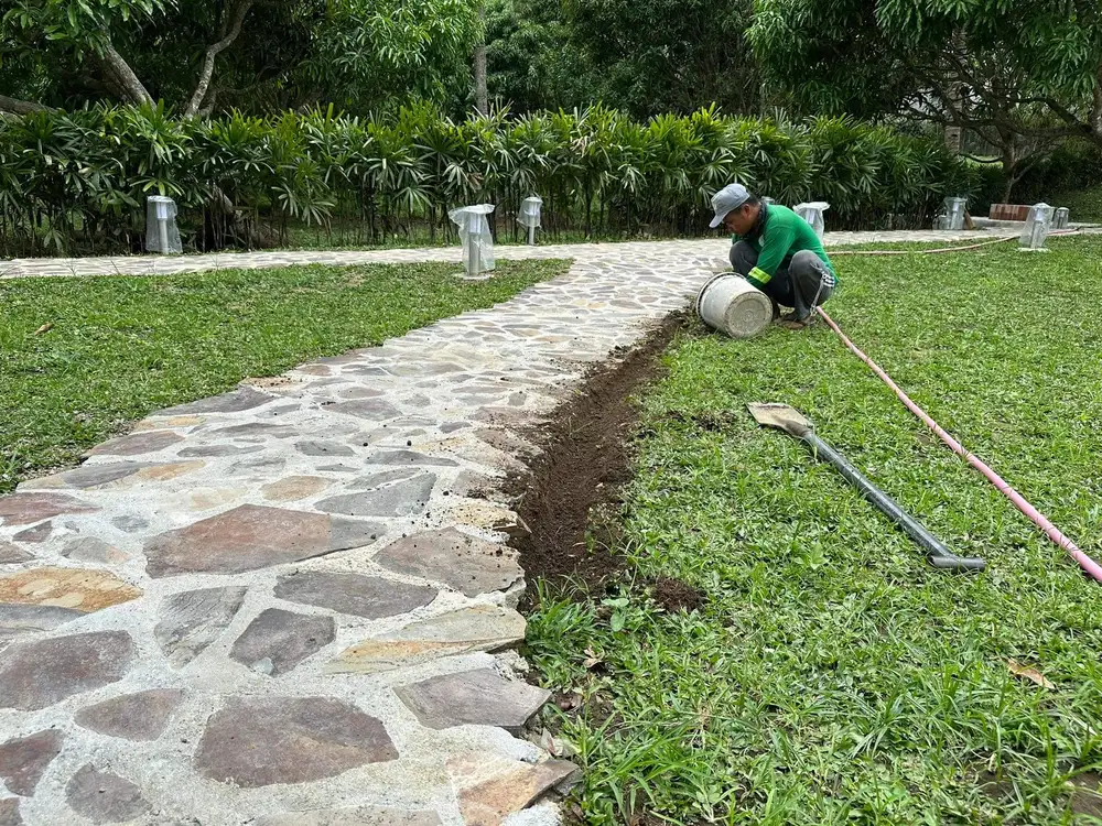 MEG gardener edging turf along a stone pathway at a private resort residence, Batangas
